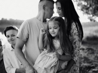 A serene black and white portrait of a family standing by a lake.